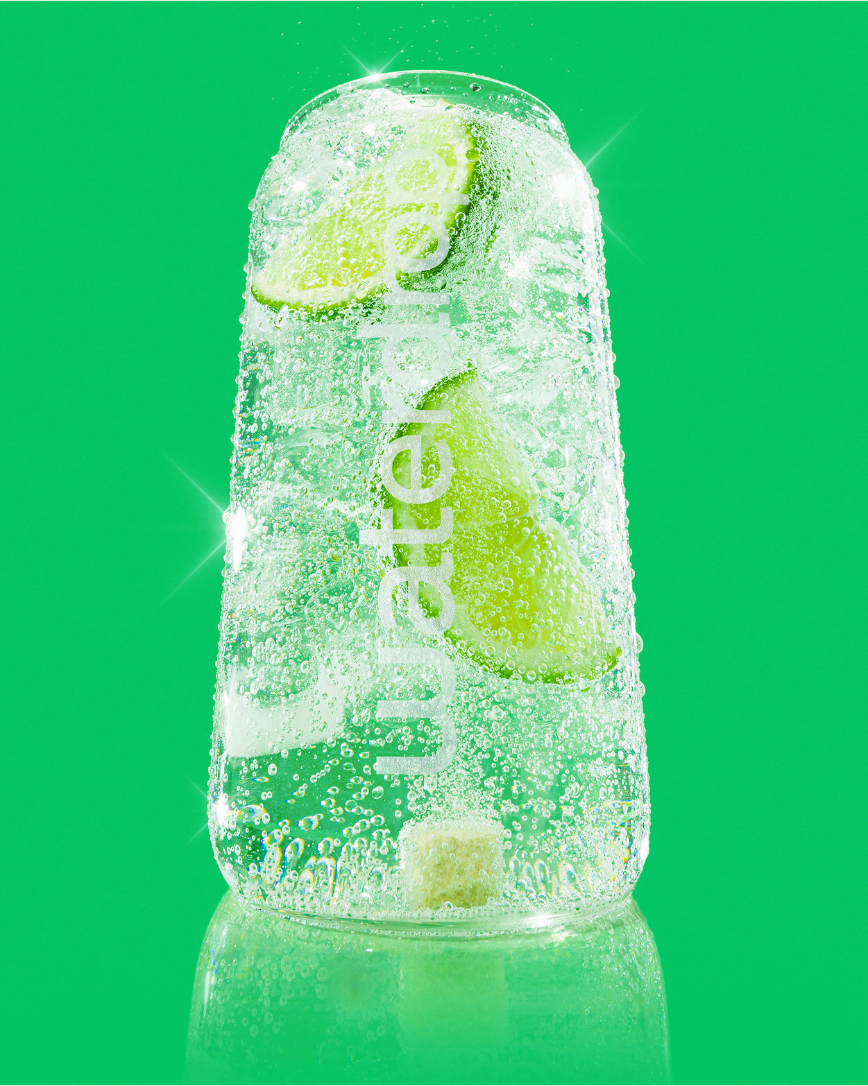 Sklenená plechovka Waterdrop naplnená perlivým nápojom s plátkami limetky a kockou Microdrink Frosted Lime, na zelenom pozadí.