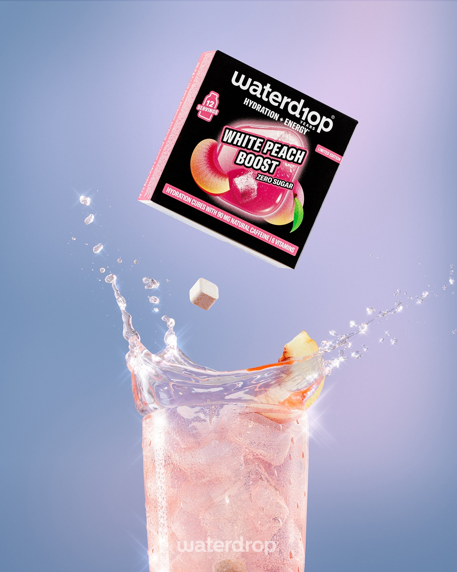 Krabica nápoja White Peach Boost nad vysokým pohárom s ružovým nápojom a ľadom.